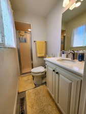 Bathroom featuring tile patterned flooring, a stall shower, vanity, baseboards, and toilet
