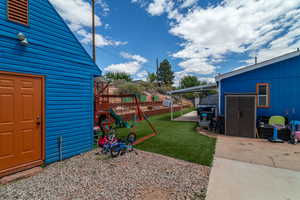View of yard with fence, an outbuilding, a patio area, and a playground