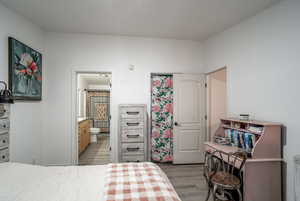 Bedroom featuring ensuite bath and light wood-style floors