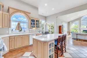 Kitchen featuring white dishwasher, light countertops, a sink, glass insert cabinets, and recessed lighting