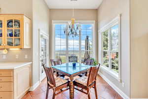 Dining area featuring baseboards, light tile patterned floors, and a notable chandelier