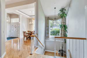 Corridor featuring baseboards, wood finished floors, and a chandelier