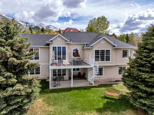 Rear view of property featuring a lawn, a patio, stucco siding, and stairway