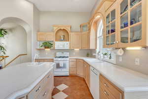Kitchen featuring a sink, light brown cabinetry, white appliances, and light countertops
