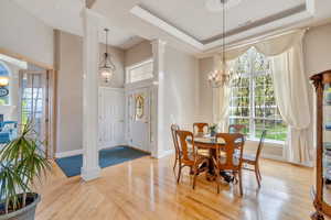 Dining area with an inviting chandelier, light wood finished floors, plenty of natural light, and baseboards