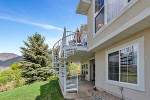 View of side of property featuring a yard, a balcony, stairs, and stucco siding