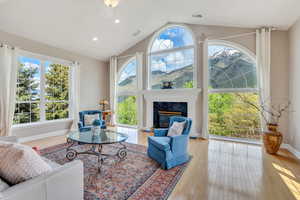 Interior space featuring visible vents, a high end fireplace, wood finished floors, baseboards, and lofted ceiling