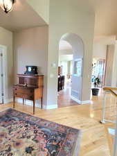 Foyer entrance with arched walkways, baseboards, light wood-type flooring, and visible vents