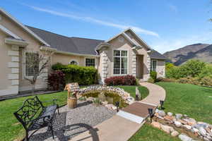 Ranch-style house featuring a shingled roof, a mountain view, stucco siding, and a front yard