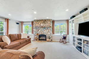 Living area featuring a textured ceiling, a fireplace, carpet floors, baseboards, and recessed lighting