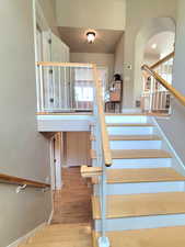 Stairs featuring arched walkways, visible vents, and wood finished floors