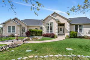 Ranch-style house with a shingled roof, stucco siding, and a front lawn