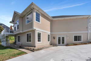 Rear view of house featuring stucco siding, french doors, and stairway