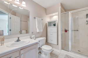 Full bathroom featuring toilet, a shower stall, tile patterned flooring, and vanity