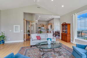 Living area with light wood-style floors, plenty of natural light, a notable chandelier, and visible vents