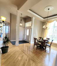 Dining area featuring decorative columns, baseboards, a notable chandelier, and light wood-style flooring