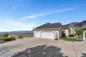 View of front of property with a mountain view, stucco siding, an attached garage, and driveway
