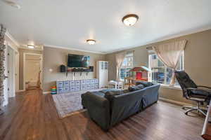 Living area featuring baseboards, ornamental molding, and wood finished floors