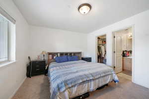 Bedroom featuring baseboards, a spacious closet, light carpet, and a closet