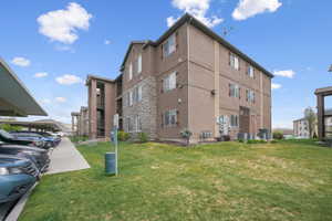 View of building exterior featuring covered parking and central AC