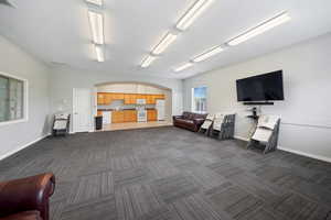 Interior space with dark carpet, arched walkways, baseboards, and visible vents