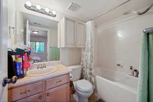 Full bathroom featuring visible vents, shower / tub combo with curtain, toilet, and vanity
