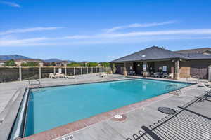 Community pool featuring fence, a mountain view, and a patio