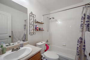 Bathroom with vanity, toilet, and shower / tub combo with curtain