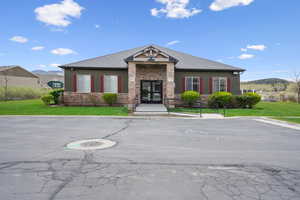 View of front of property with a front lawn, uncovered parking, and stone siding