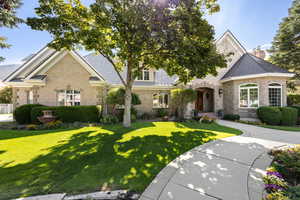 View of front of home with stone siding, a chimney, a front lawn, and brick siding