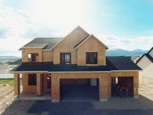 View of front of home featuring an attached garage, a shingled roof, a mountain view, and covered porch
