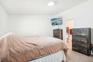 Bedroom with beverage cooler, ensuite bath, and light colored carpet