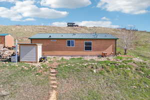 Rear view of house featuring a storage unit and metal roof