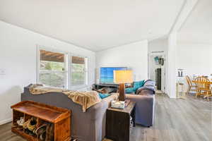Living room featuring baseboards, vaulted ceiling, wood finished floors, and visible vents