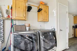 Laundry area with cabinet space, independent washer and dryer, and wood finished floors