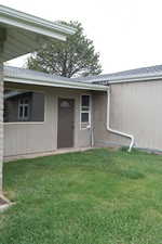 Entrance to property with a lawn and roof with shingles