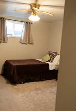 Carpeted bedroom with a ceiling fan
