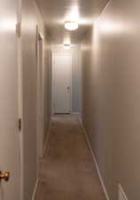 Corridor featuring baseboards and light colored carpet