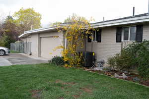 View of home's exterior featuring a garage, concrete driveway, a yard, and brick siding