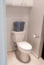 Bathroom with toilet, tile patterned floors, and baseboards