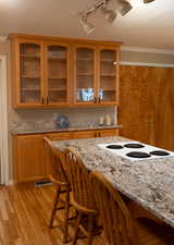 Kitchen featuring crown molding, light stone counters, light wood finished floors, a breakfast bar area, and visible vents