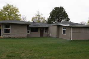 Back of house featuring a lawn and a chimney