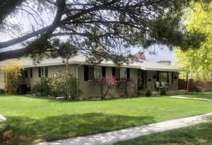 View of front of house with covered porch, a chimney, central AC unit, and a front yard