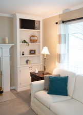 Living room featuring built in features, ornamental molding, and light colored carpet