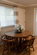 Dining space featuring baseboards, ornamental molding, and light wood-style flooring