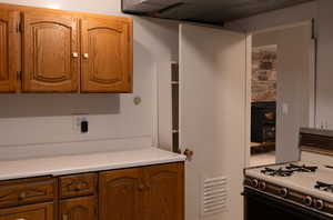 Kitchen featuring light countertops, brown cabinets, and white range with gas cooktop