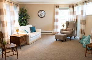 Sitting room featuring a baseboard heating unit, ornamental molding, and carpet