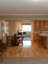 Dining space with crown molding, a textured ceiling, and light wood-type flooring