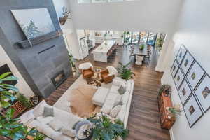 Living room with a tiled fireplace, baseboards, a towering ceiling, and wood finished floors