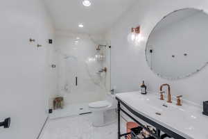 Bathroom featuring recessed lighting, a marble finish shower, toilet, and vanity